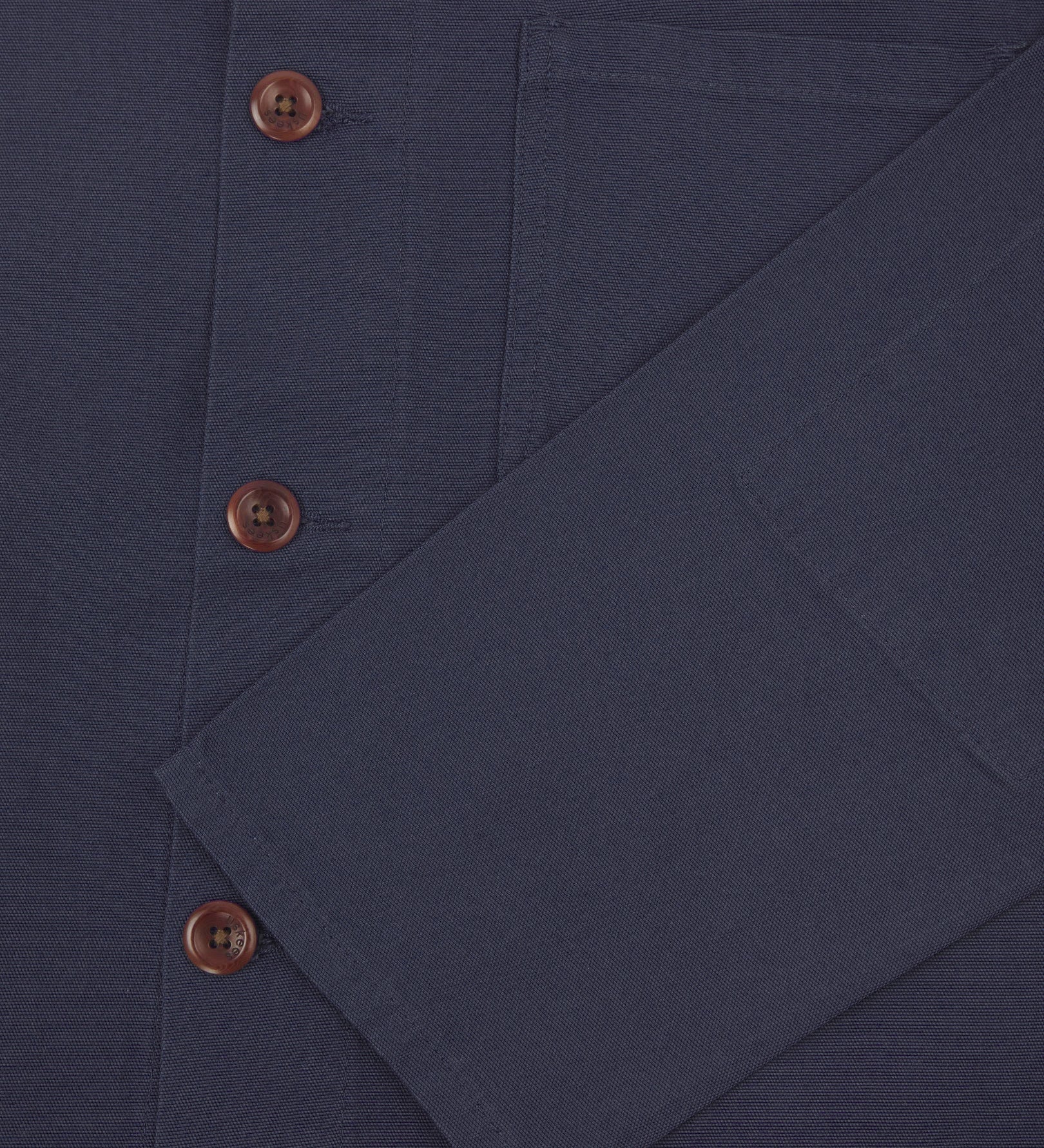 Closer view of mid section of midnight blue, buttoned organic cotton overshirt from Uskees. Focus on cuff, pockets and corozo buttons.