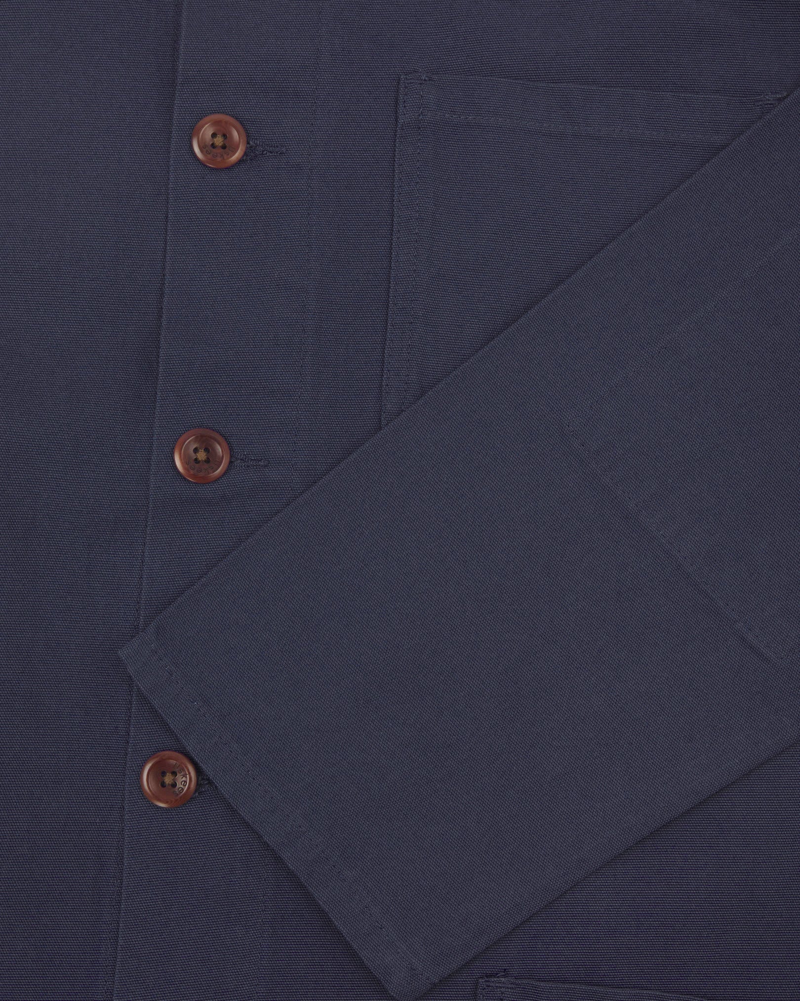 Closer view of mid section of midnight blue, buttoned organic cotton overshirt from Uskees. Focus on cuff, pockets and corozo buttons.