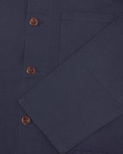 Closer view of mid section of midnight blue, buttoned organic cotton overshirt from Uskees. Focus on cuff, pockets and corozo buttons.