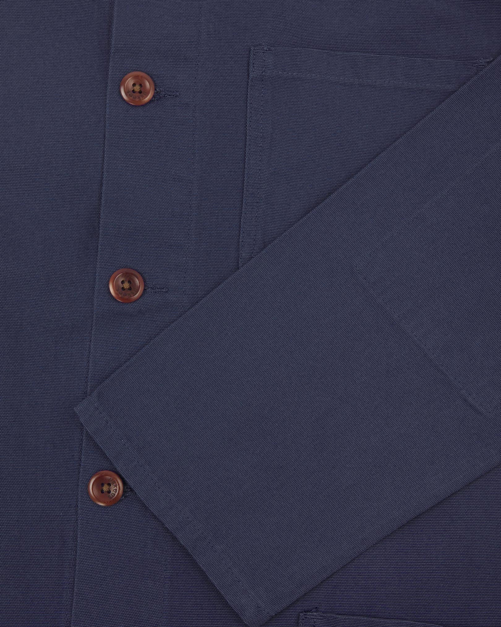Closer view of mid section of midnight blue, buttoned organic cotton overshirt from Uskees. Focus on cuff, pockets and corozo buttons.