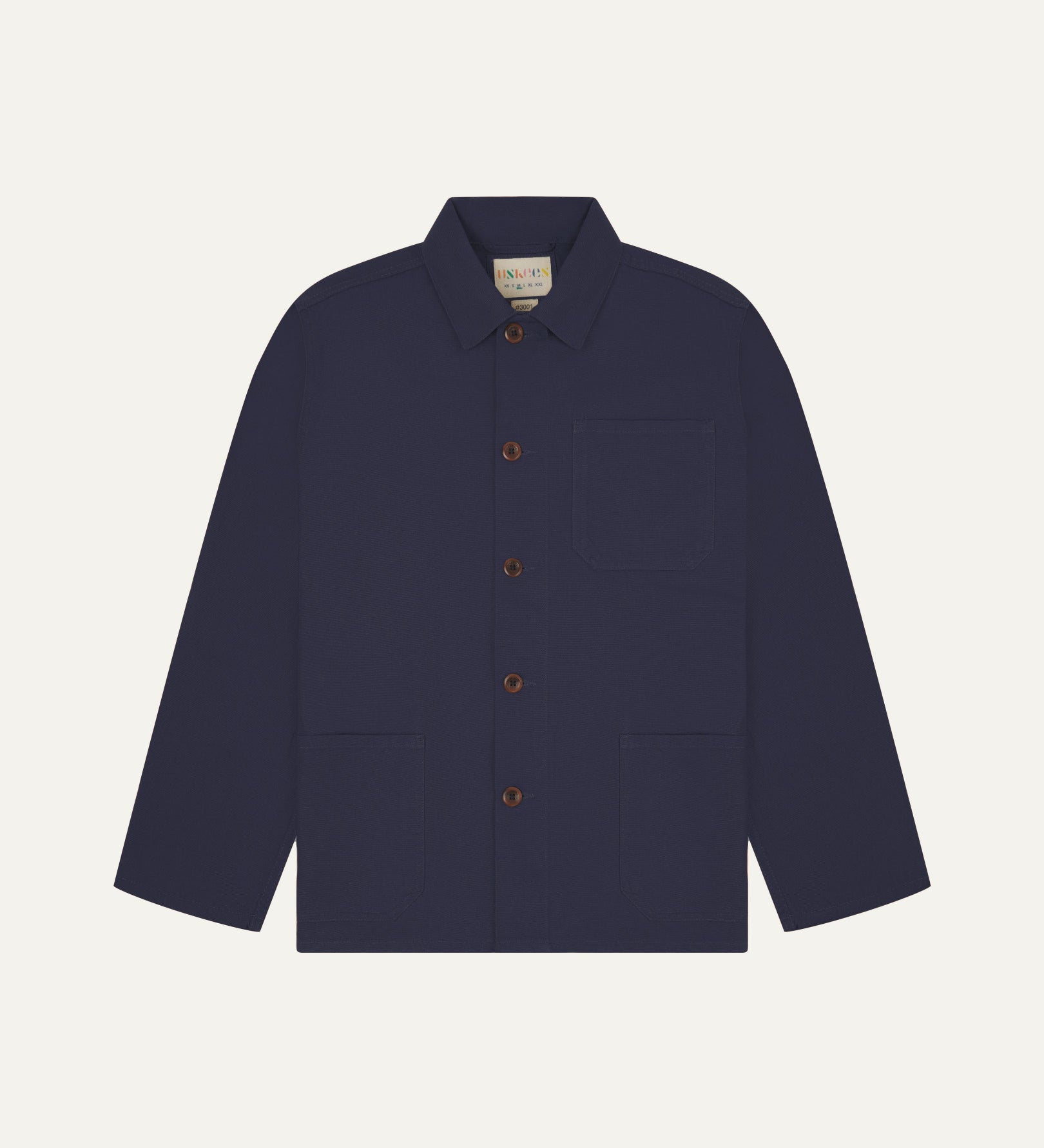 Front flat shot of midnight blue, buttoned organic cotton overshirt. Clear view of chest and hip pockets, corozo buttons and Uskees branding label.