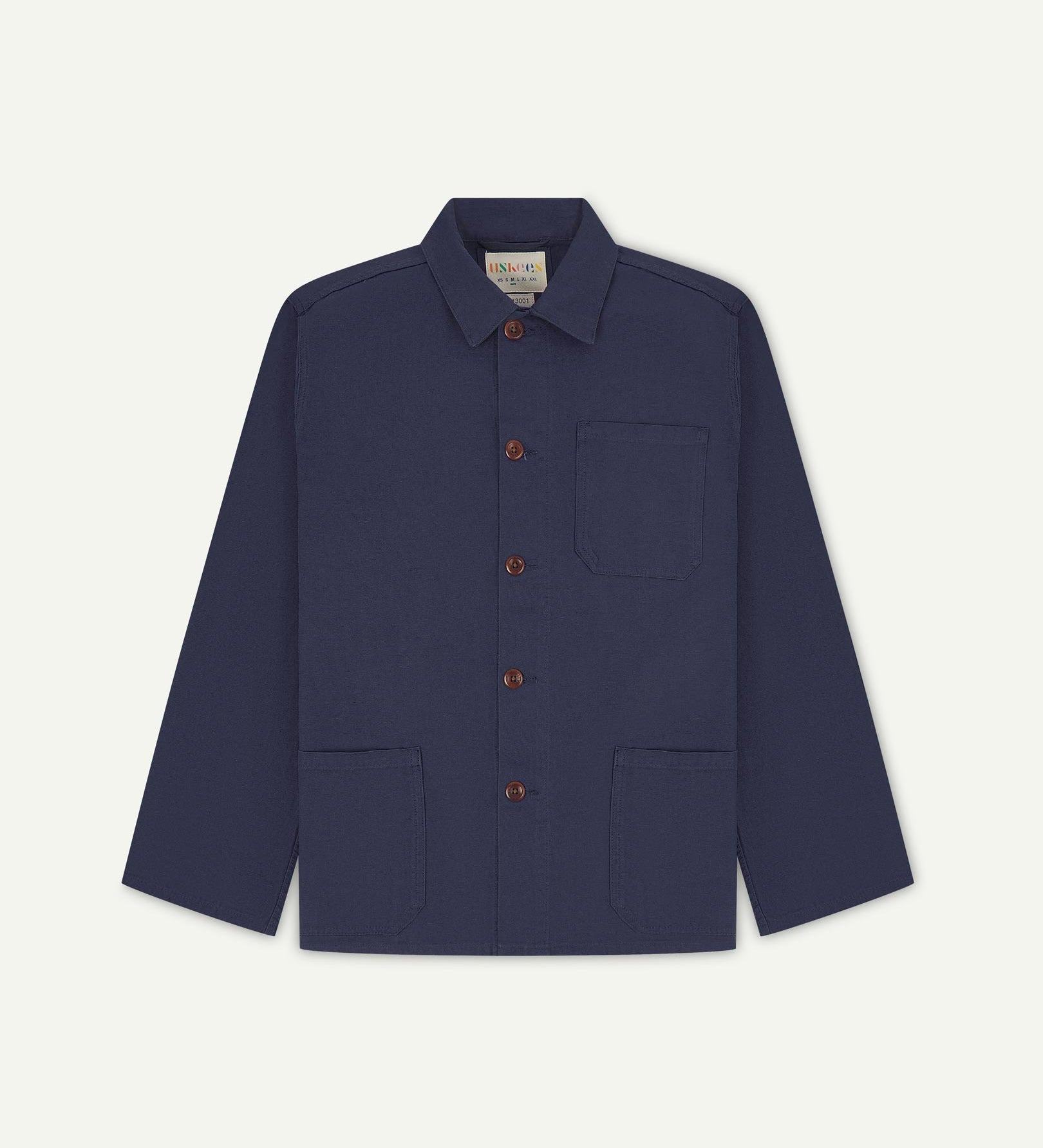 Front flat shot of midnight blue, buttoned organic cotton overshirt. Clear view of chest and hip pockets, corozo buttons and Uskees branding label.