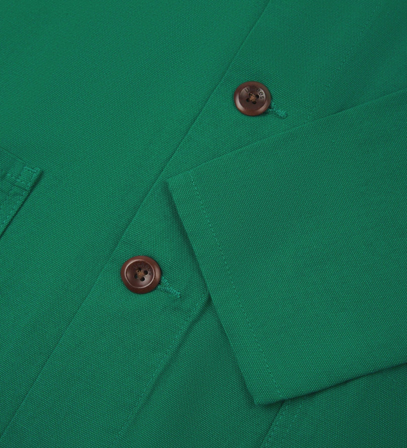 Closer view of mid section of mint green, buttoned organic cotton overshirt from Uskees. Focus on cuff, placket and corozo buttons.