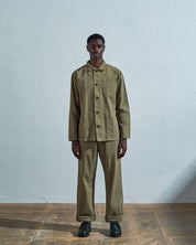 Full-length front view of model wearing #3001 moss-green-coloured organic cotton-drill overshirt, showing secured corozo buttons and paired with matching Uskees pants.