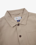 Close-up top-half view of #3001 oatmeal (beige) organic cotton drill overshirt. With focus on collar, Uskees brand label and corozo buttons.