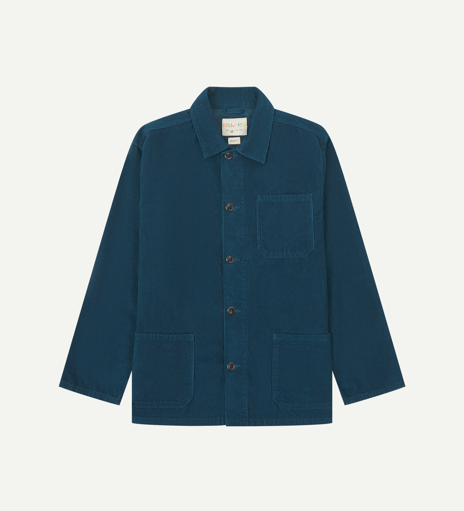 Front flat shot of petrol blue, buttoned corduroy overshirt. Clear view of chest and hip pockets, corozo buttons and Uskees branding label.