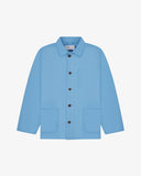 Front flat shot of powder blue, buttoned organic cotton overshirt. Clear view of chest and hip pockets, corozo buttons and Uskees branding label.