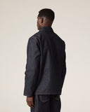 Back view of male model wearing Uskees raw orta denim workwear pants in dark indigo with matching denim overshirt. 
