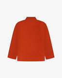 Back view of rust-red, buttoned corduroy overshirt with view of reinforced elbow area and boxy silhouette.