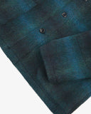 Closer view of mid section of peacock blue check, buttoned Pennine wool overshirt from Uskees. Focus on cuff, pocket, corozo button and Pennine wool texture.