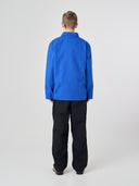 Full-length back view of man wearing an Uskees ultra blue cotton overshirt paired with dark pants, showing reinforced elbows.