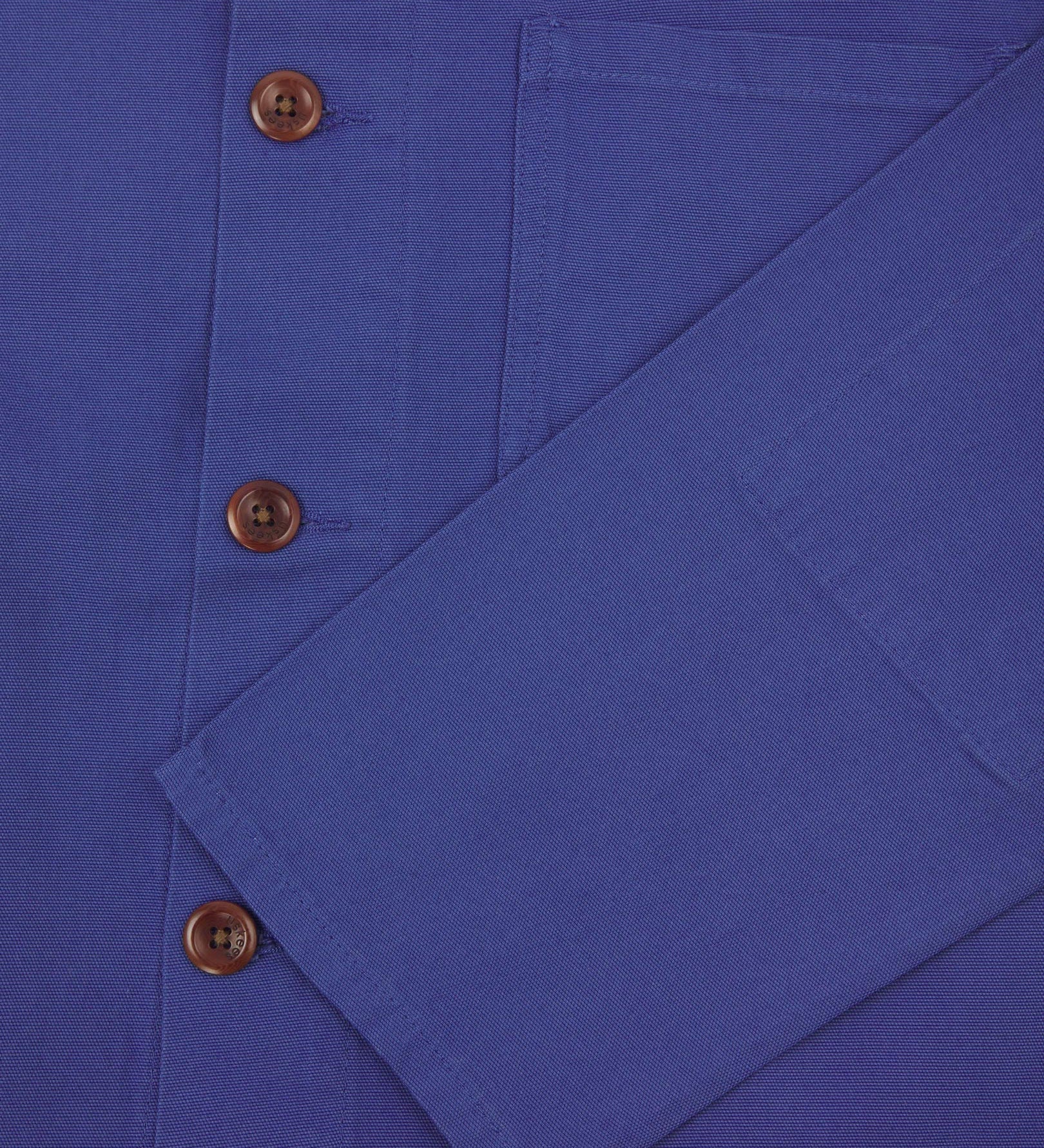 Closer view of mid section of ultra blue, buttoned organic cotton overshirt from Uskees. Focus on cuff, pockets and corozo buttons.