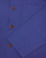 Closer view of mid section of ultra blue, buttoned organic cotton overshirt from Uskees. Focus on cuff, pockets and corozo buttons.