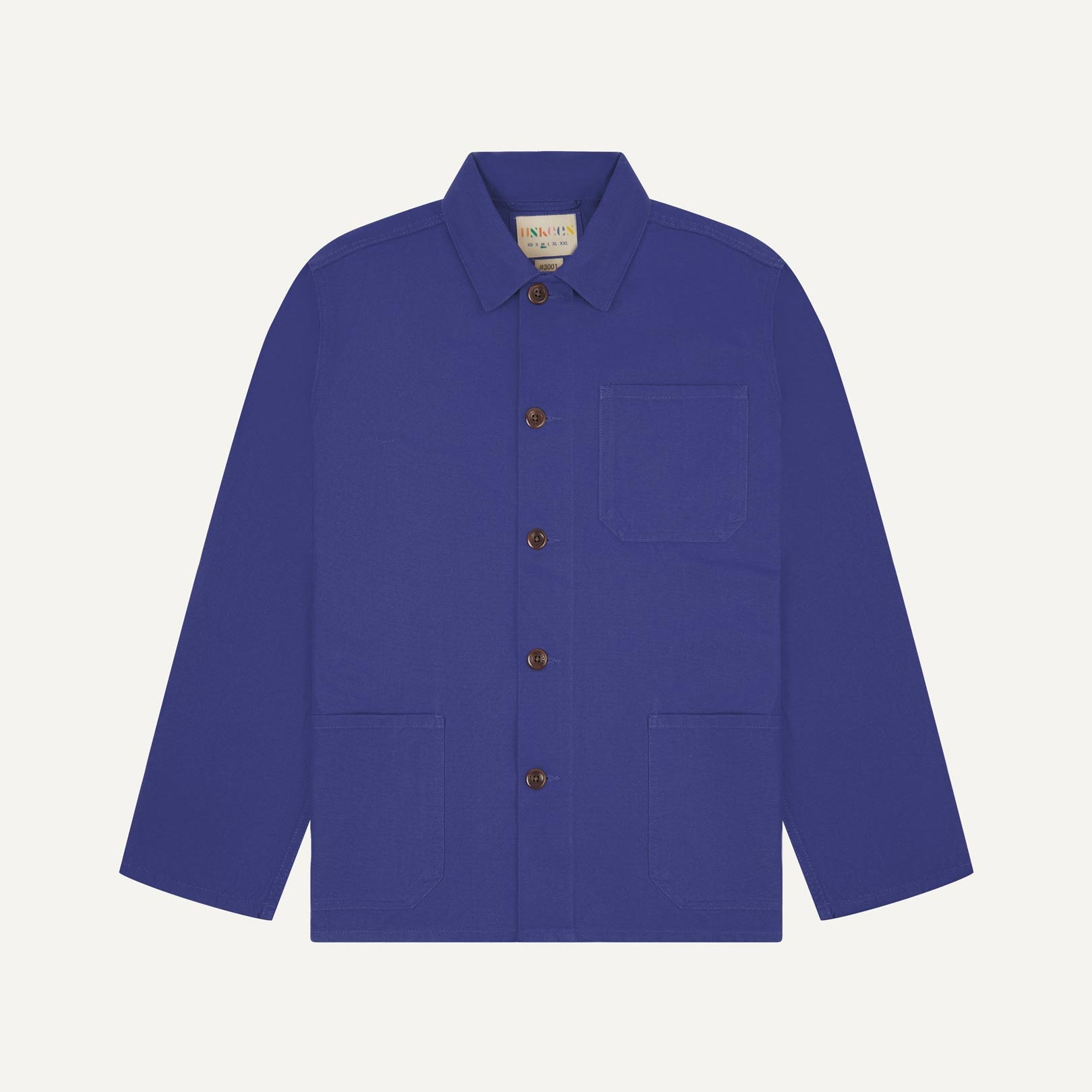 Front flat shot of ultra blue, buttoned organic cotton overshirt. Clear view of chest and hip pockets, corozo buttons and Uskees branding label.
