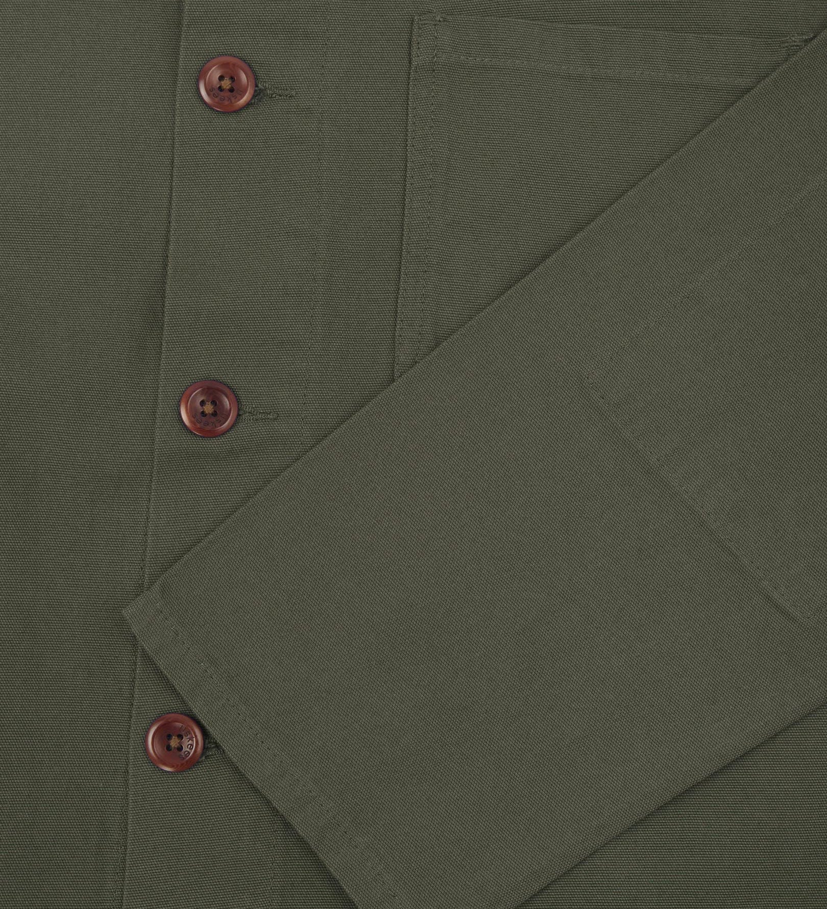 Closer view of mid section of vine green, buttoned organic cotton overshirt from Uskees. Focus on cuff, pockets and corozo buttons.