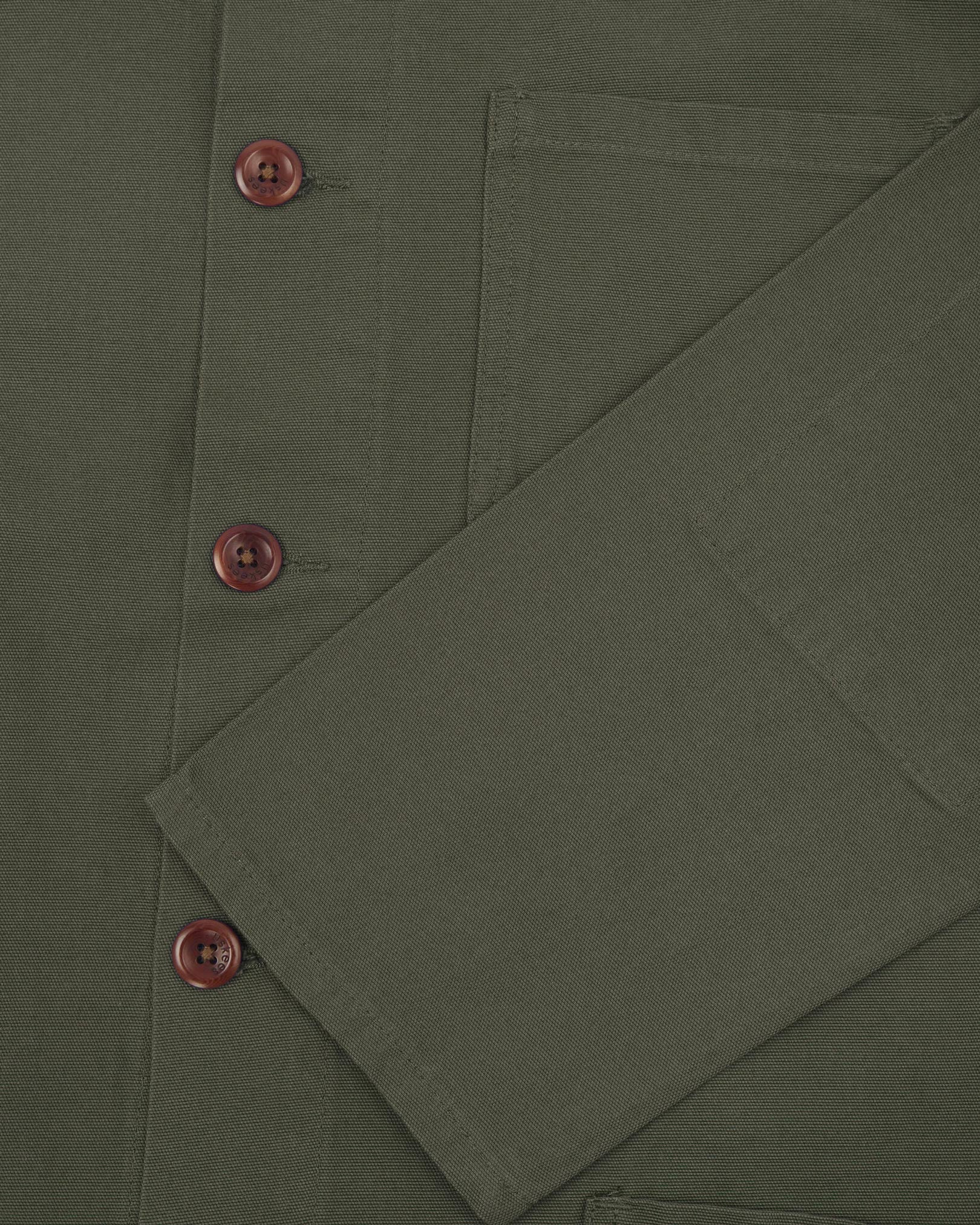 Closer view of mid section of vine green, buttoned organic cotton overshirt from Uskees. Focus on cuff, pockets and corozo buttons.