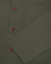 Closer view of mid section of vine green, buttoned organic cotton overshirt from Uskees. Focus on cuff, pockets and corozo buttons.