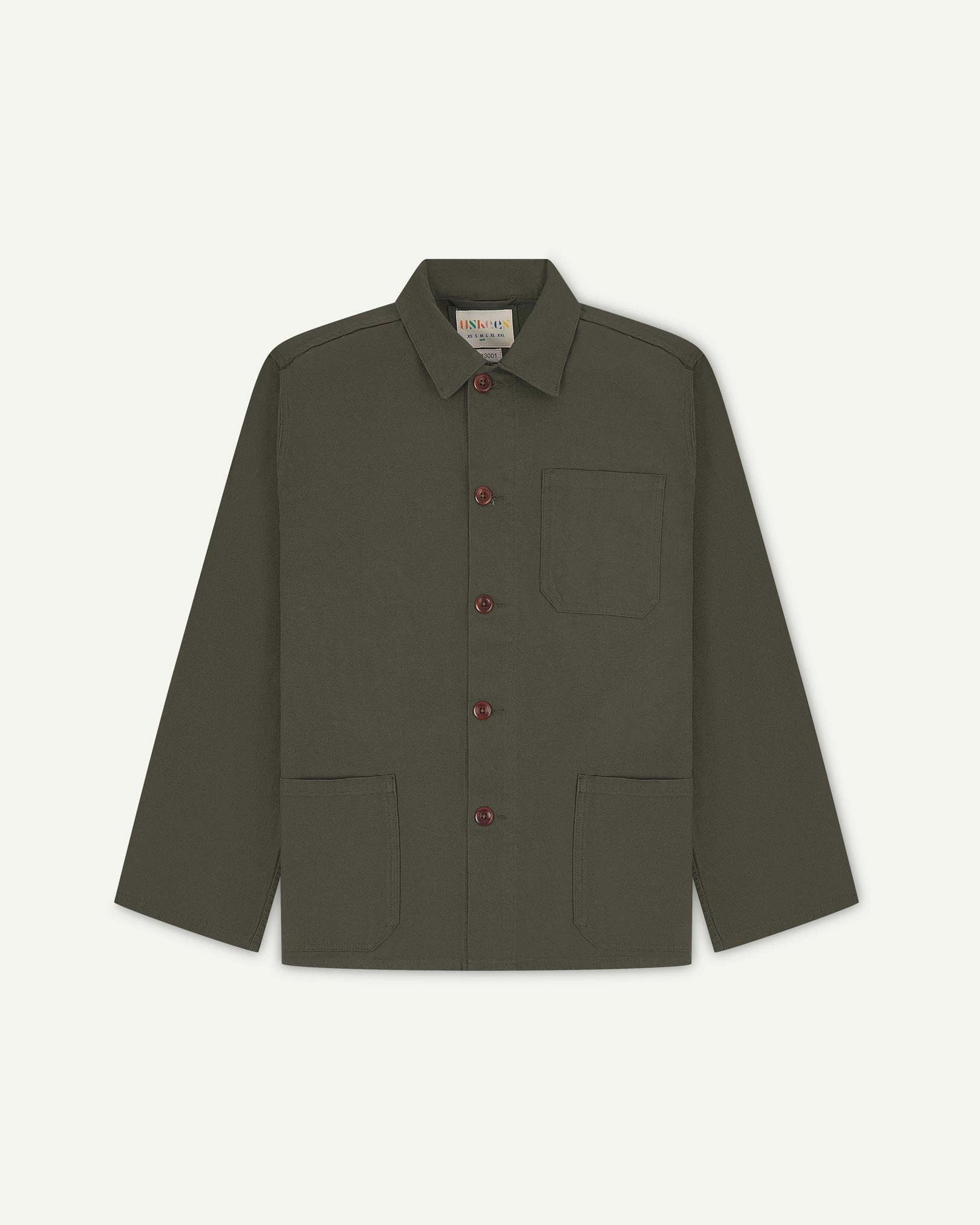 Front flat shot of vine green, buttoned organic cotton overshirt. Clear view of chest and hip pockets, corozo buttons and Uskees branding label.