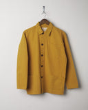Yellow buttoned organic cotton overshirt from Uskees presented on hanger. Clear view of breast and hip pocket and corozo buttons.