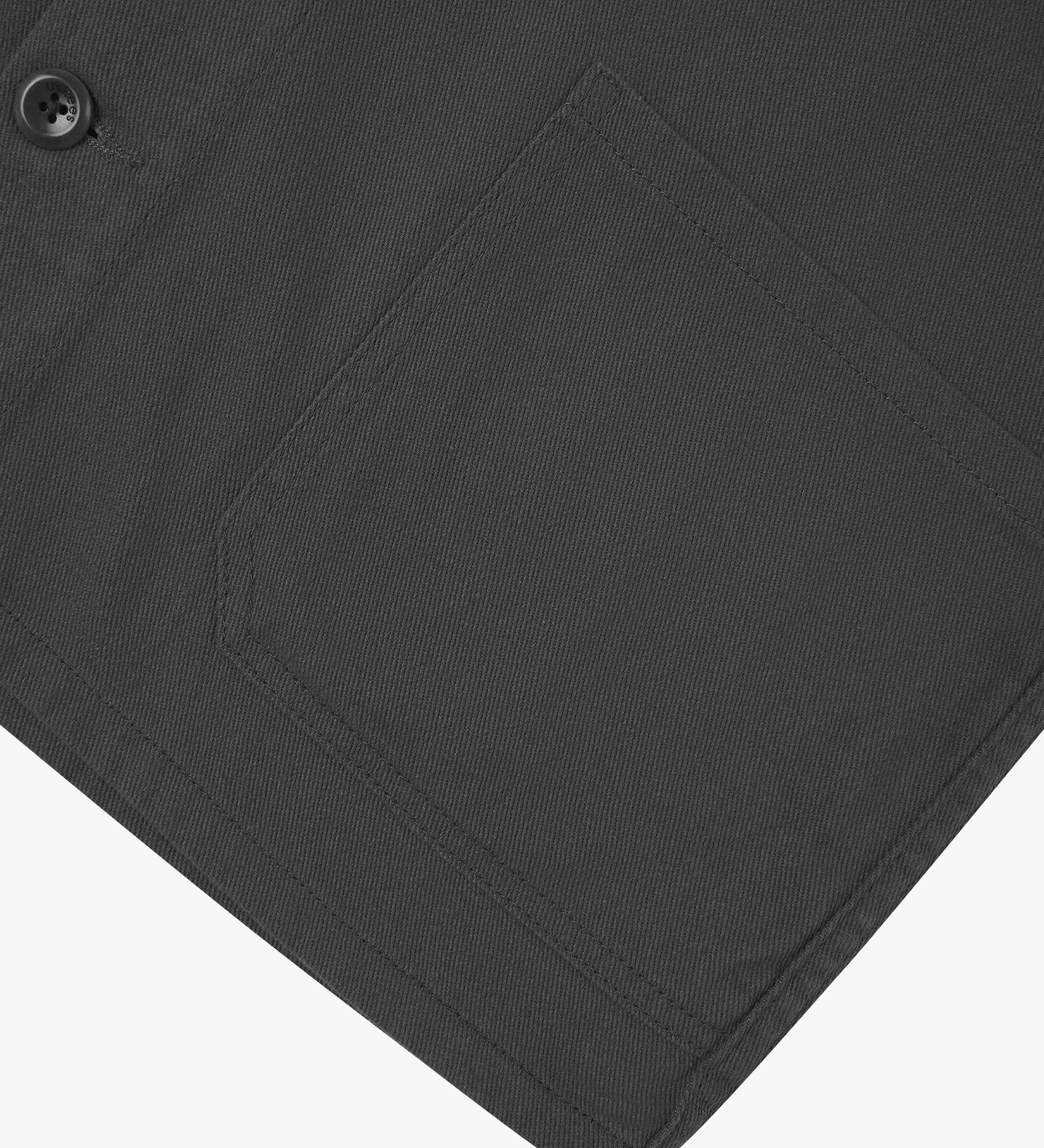 View of the mid-section and sleeve of the 3001 Uskees button-down drill overshirt in charcoal-grey with focus on hem and hip pocket.