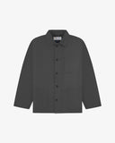 Front flat shot of charcoal-grey, buttoned drill overshirt. Clear view of corozo buttons, 3 pockets and Uskees branding label.