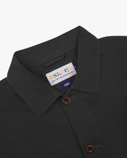 Close-up view of 3001 charcoal-grey, buttoned organic cotton overshirt from Uskees showing corozo buttons, brand label, collar and hanging hoop.