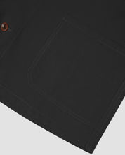 Closer view of mid section of charcoal-grey, buttoned organic cotton overshirt from Uskees. Focus on cuff, pockets and corozo buttons.