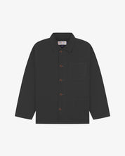 Front flat shot of charcoal-grey, buttoned organic cotton overshirt. Clear view of chest and hip pockets, corozo buttons and Uskees branding label.