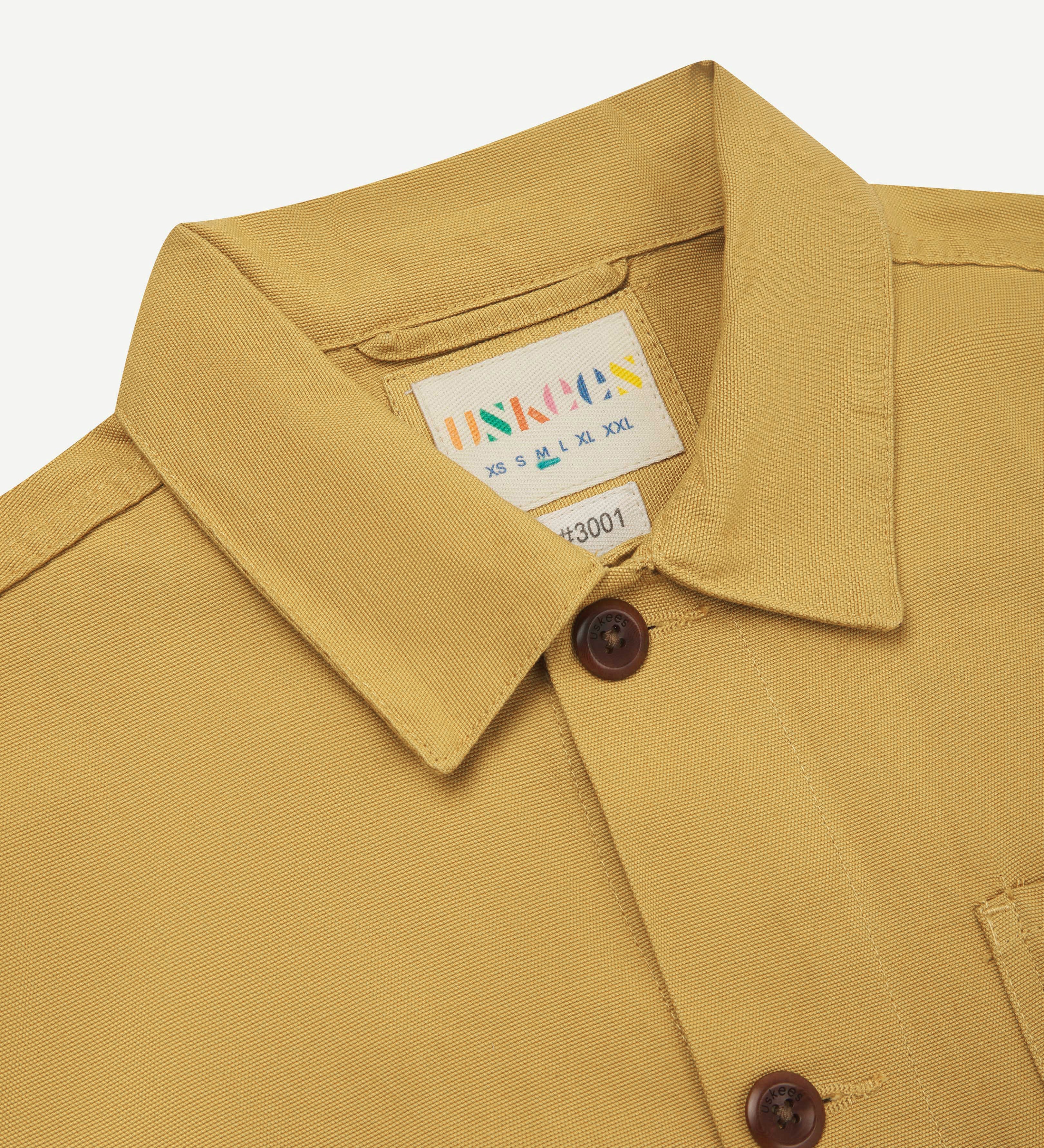 Close up front view of yellow men's overshirt with buttons done up and showing collar and uskees brand  label