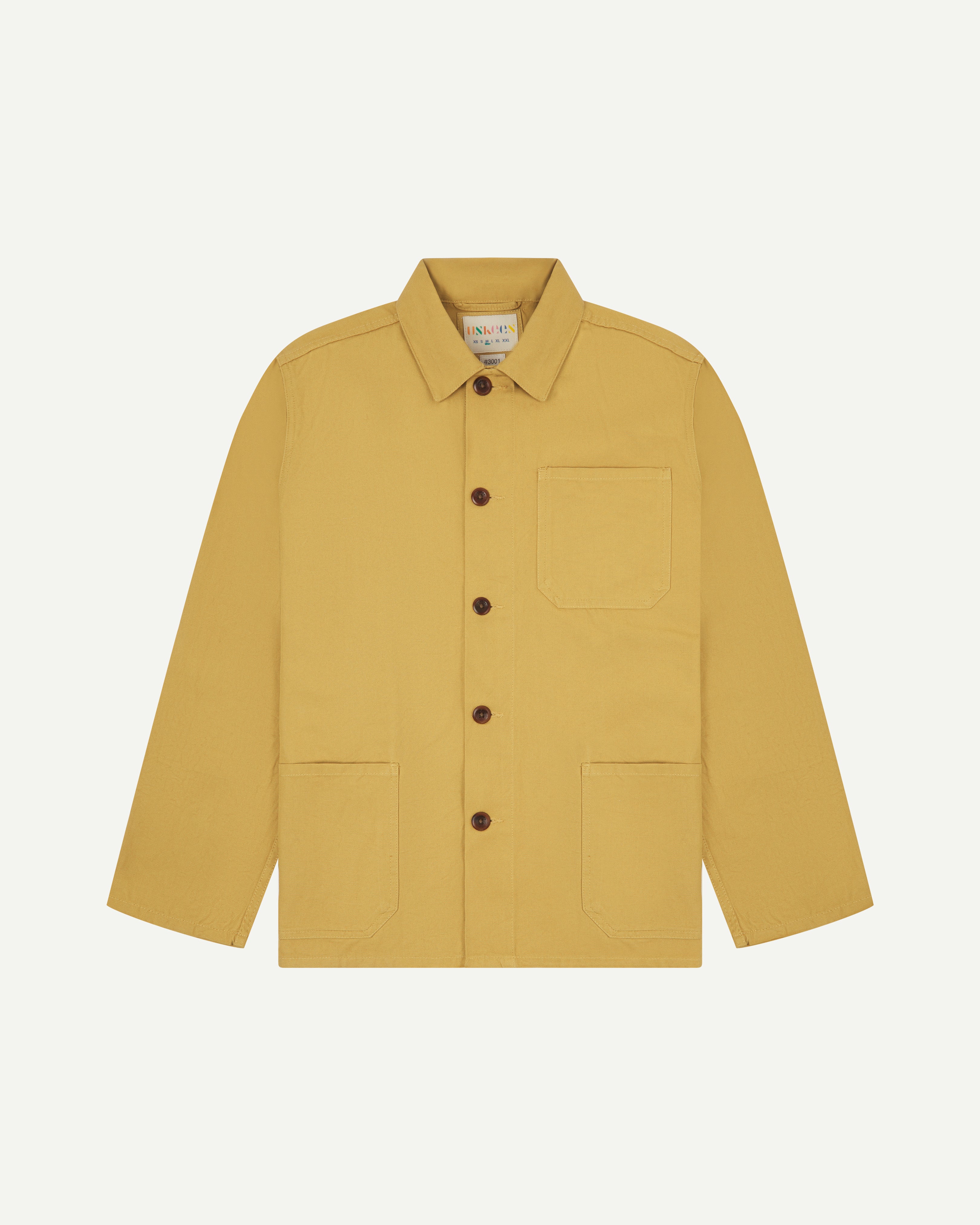 Flat shot of the front of a yellow men's overshirt with buttons done up and showing uskees neck label
