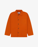 Front flat shot of golden-orange, buttoned organic cotton overshirt. Clear view of chest and hip pockets, corozo buttons and Uskees branding label.