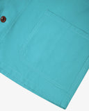 Close-up of a aqua blue shirt-jacket pocket and brown Corozo button on a white background