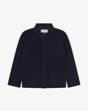 Front flat shot of an Uskees dark blue corduroy utility shirt jacket showing the three front pockets.