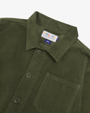 Close up view of Uskees green corduroy shirt-jacket for men showing button and brand label details.