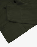Close up flat view of Uskees dark green drill shirt-jacket for men showing the Corozo buttons,pocket and cuff on a light gray background