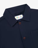 Close-up view of 3001 midnight blue, buttoned organic cotton overshirt from Uskees showing corozo buttons, brand label, collar and hanging loop.
