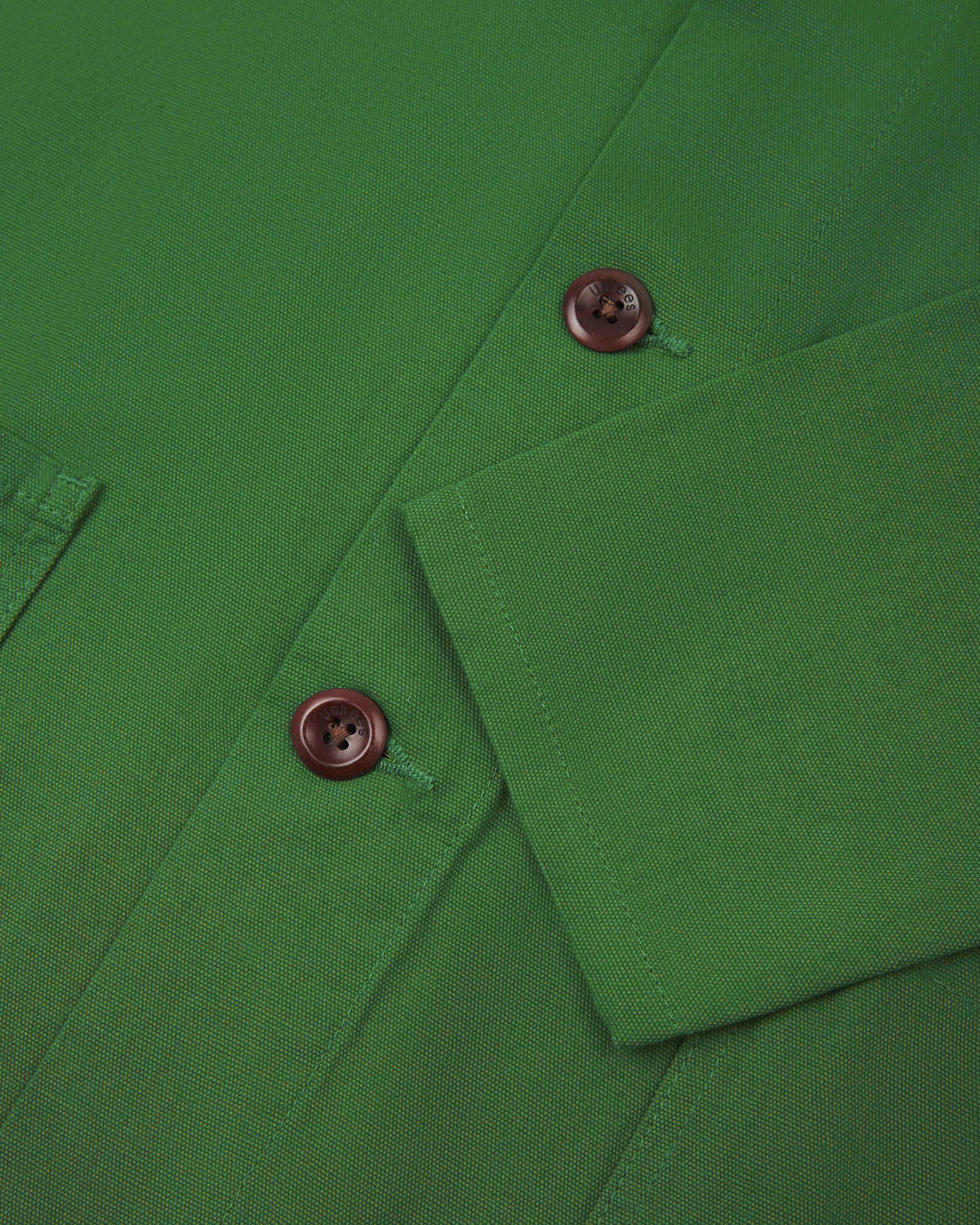 Closer view of mid section of mint green, buttoned organic cotton overshirt from Uskees. Focus on cuff, placket and corozo buttons.
