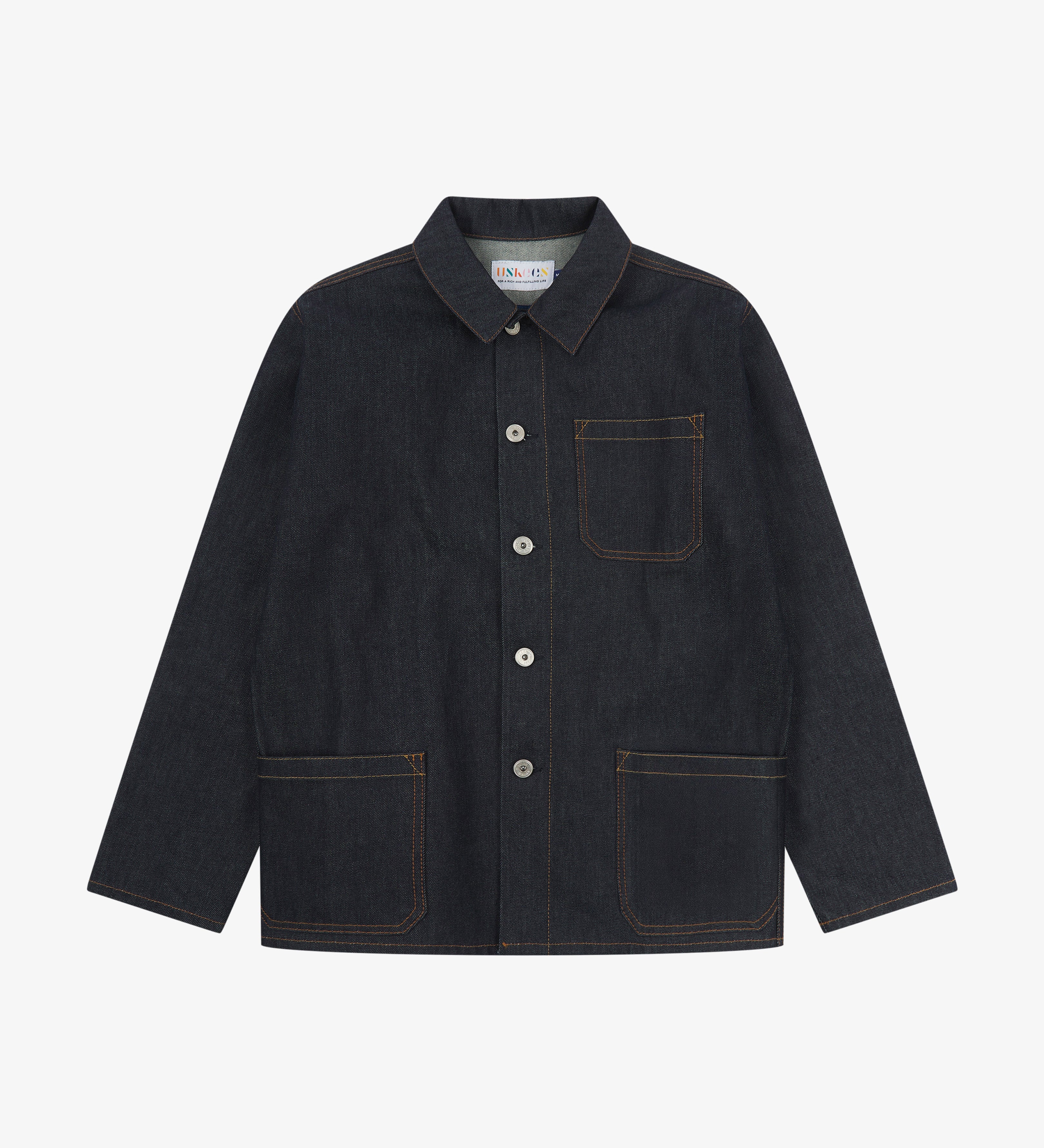 Front flat shot of the dark indigo, raw orta denim buttoned overshirt. Clear view of nickel-free buttons, 3 pockets and reinforced elbows.