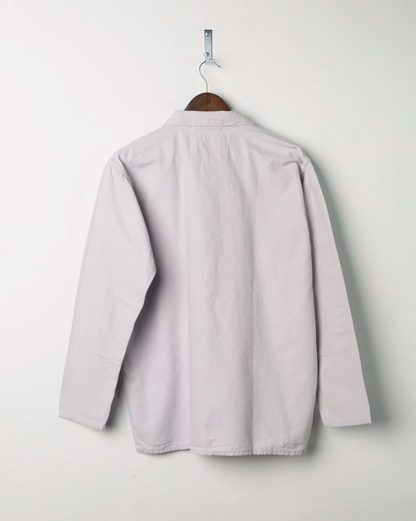 Back view of the #3002 light-grey zip jacket displayed on a hanger, showing reinforced elbows and simple silhouette.