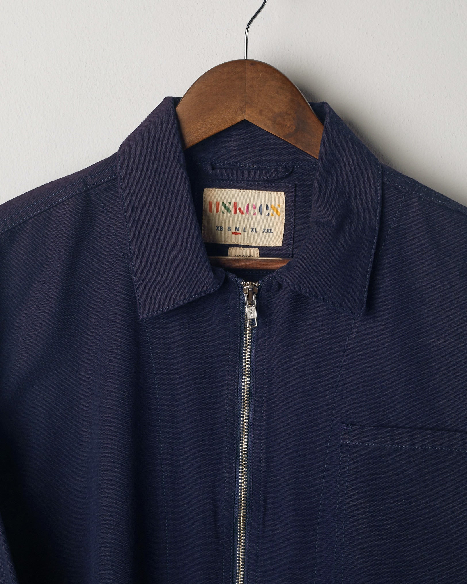 Close-up view of the collar of the Uskees #3002, midnight blue zip-front jacket. Zipped up to demonstrate collar shape and boxy jacket silhouette.