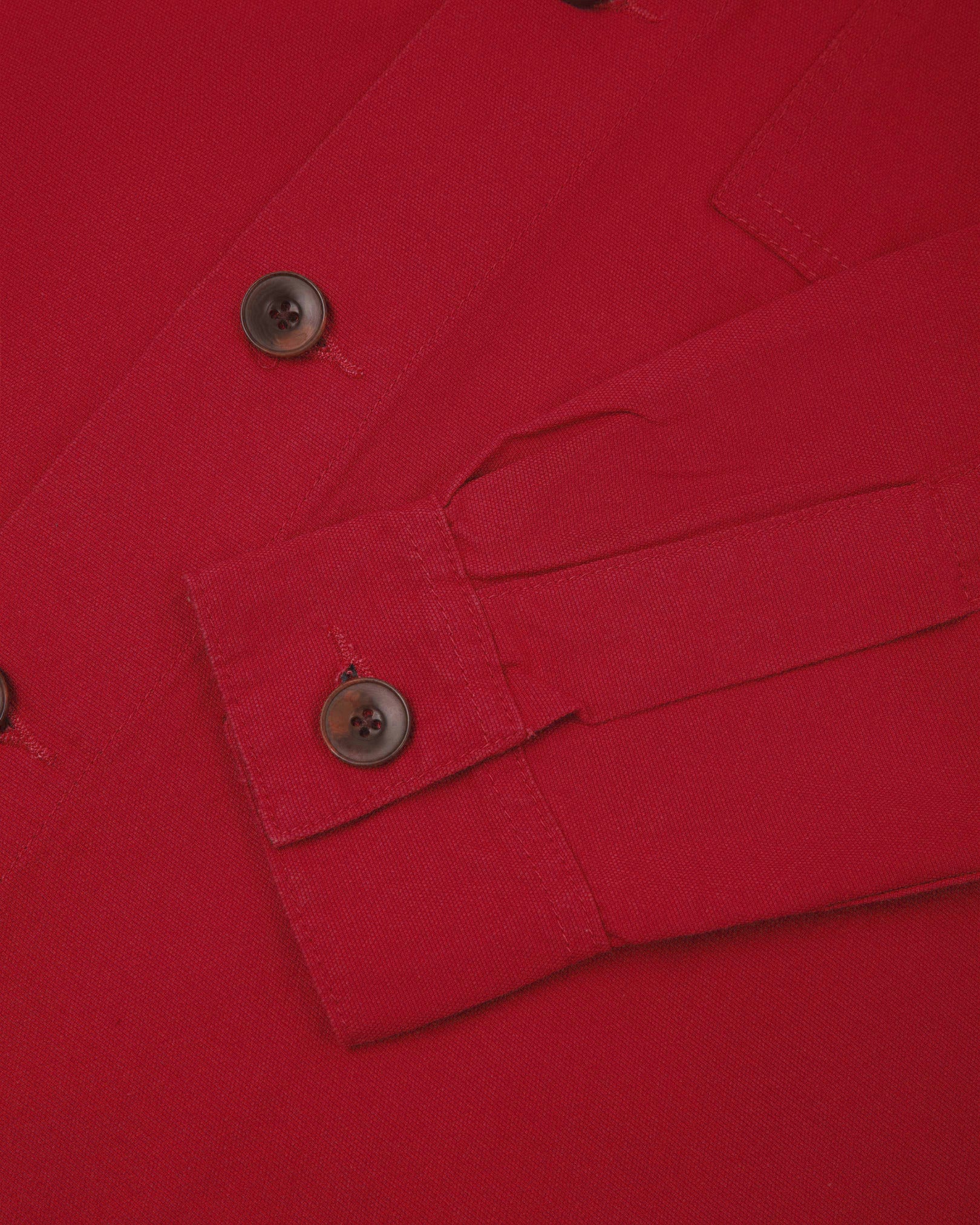 View of the mid-section and sleeve of the 3003 Uskees button-down work shirt in berry red with focus on cuff, placket and corozo buttons.