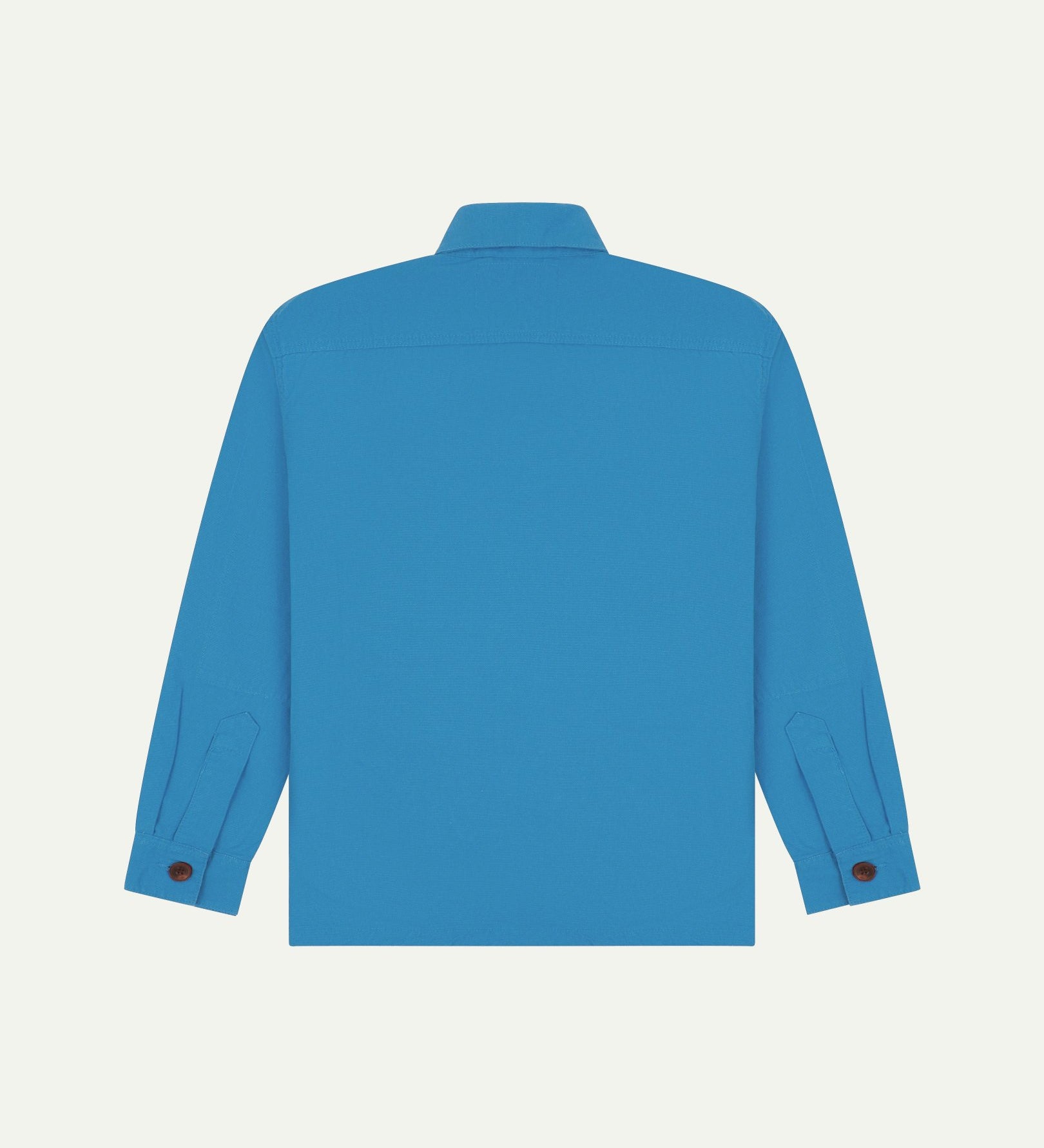 Reverse of bright blue buttoned organic cotton workshirt from Uskees showing reinforced elbows, tailored cuffs and boxy silhouette.