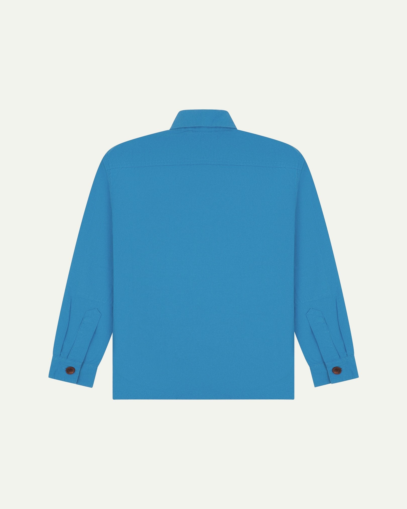 Reverse of bright blue buttoned organic cotton workshirt from Uskees showing reinforced elbows, tailored cuffs and boxy silhouette.