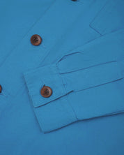 View of the mid-section and sleeve of the 3003 Uskees button-down work shirt in bright blue with focus on cuff, placket and corozo buttons.