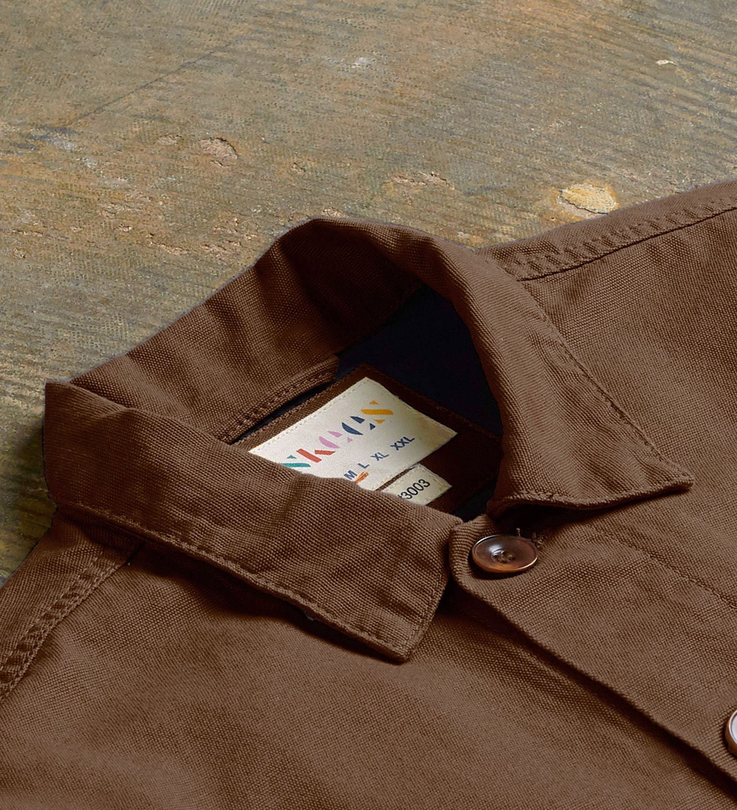 Angled flat view of the collar of the #3003 Uskees button-down work shirt in brown, showing weave of organic cotton and Uskees branding label