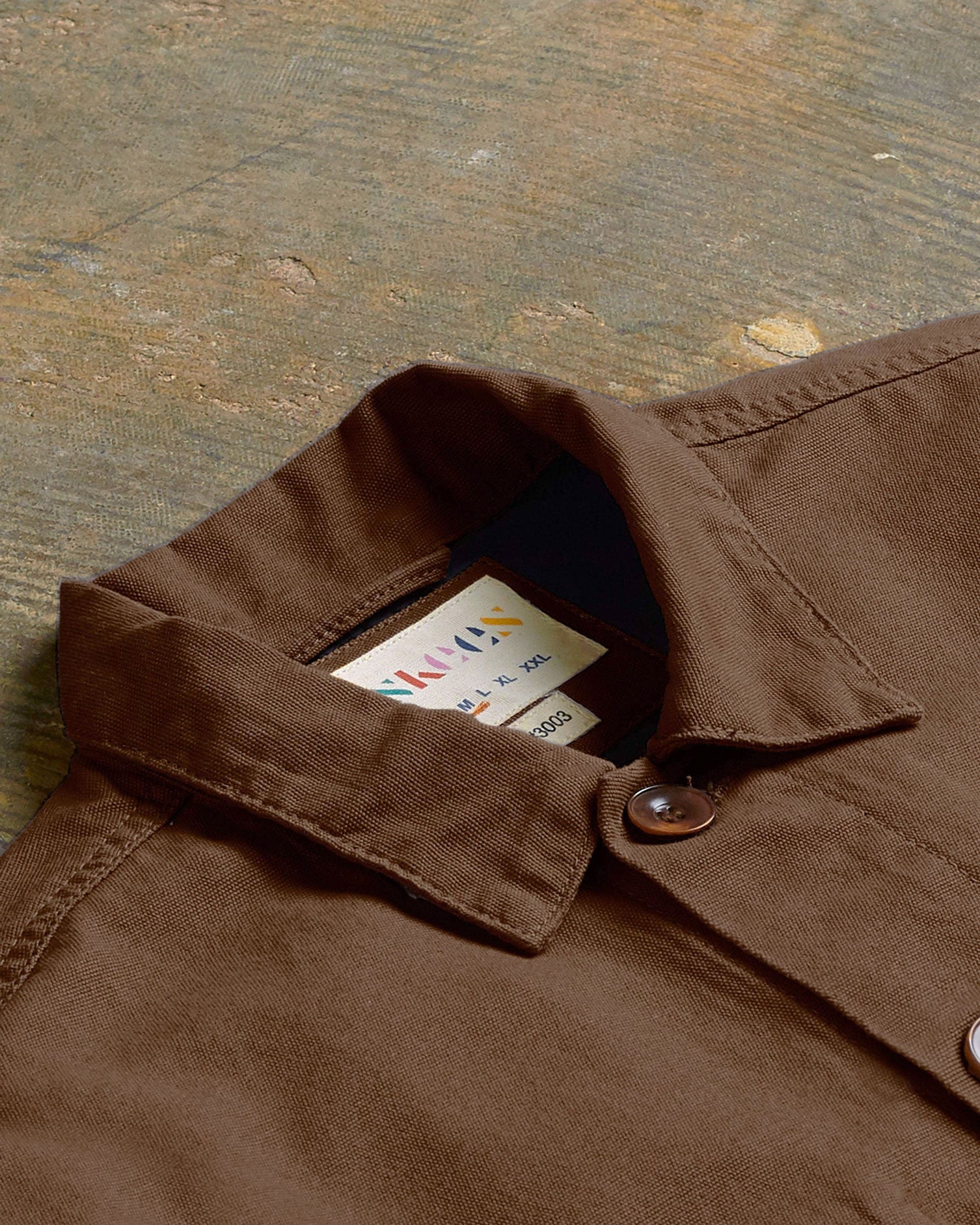 Angled flat view of the collar of the #3003 Uskees button-down work shirt in brown, showing weave of organic cotton and Uskees branding label