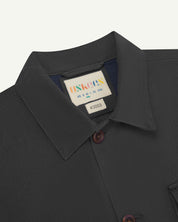 Close-up top-half view of #3003, charcoal organic cotton workshirt. With focus on collar, Uskees brand label and corozo buttons.