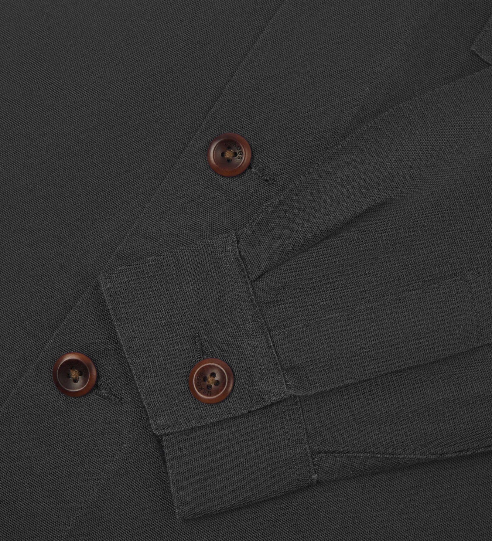 View of the mid-section and sleeve of the 3003 Uskees button-down work shirt in charcoal with focus on cuff, placket and corozo buttons.