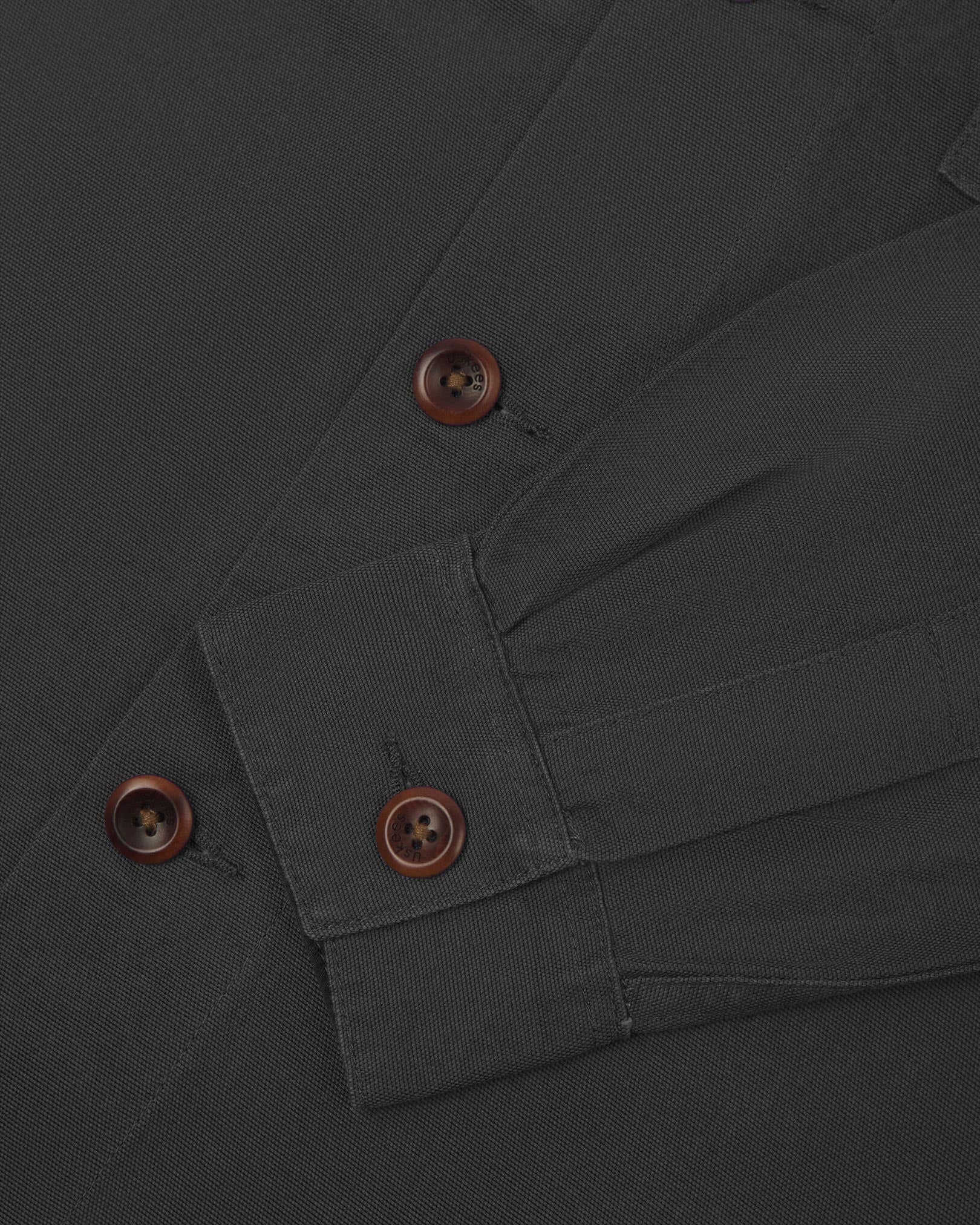 View of the mid-section and sleeve of the 3003 Uskees button-down work shirt in charcoal with focus on cuff, placket and corozo buttons.