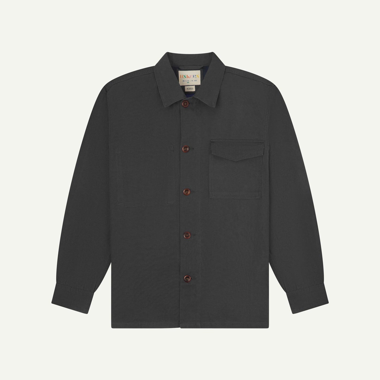 Charcoal buttoned organic cotton overshirt from Uskees with clear view of chest pocket and Uskees branding label.